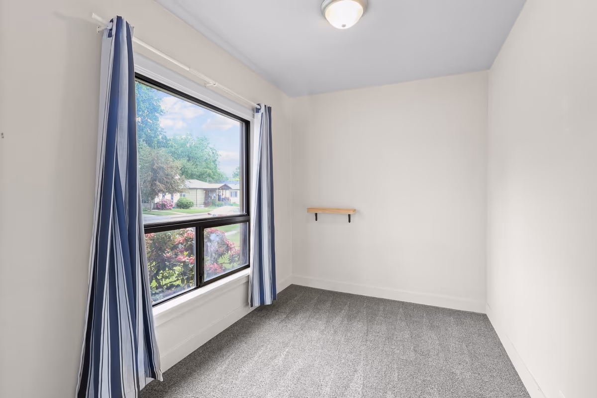 Bright bedroom with a large window and striped drapes