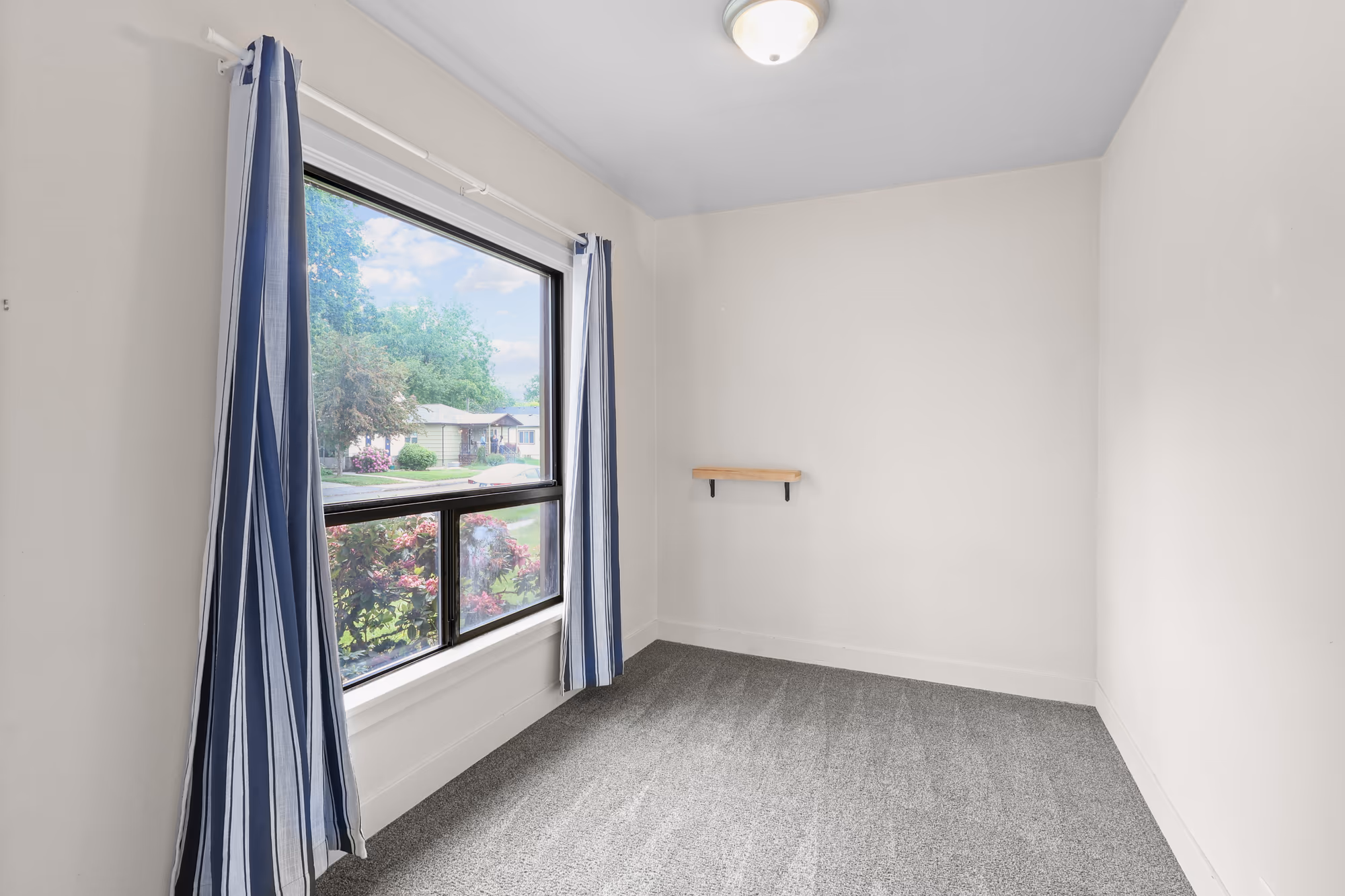 Bright bedroom with a large window and striped drapes