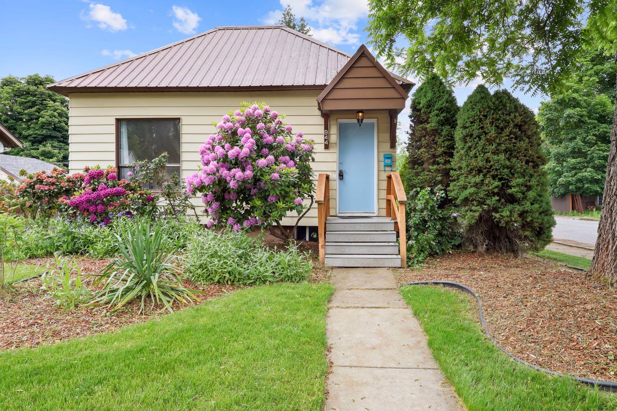 Cottage-style home with flowering landscaping and a walkway