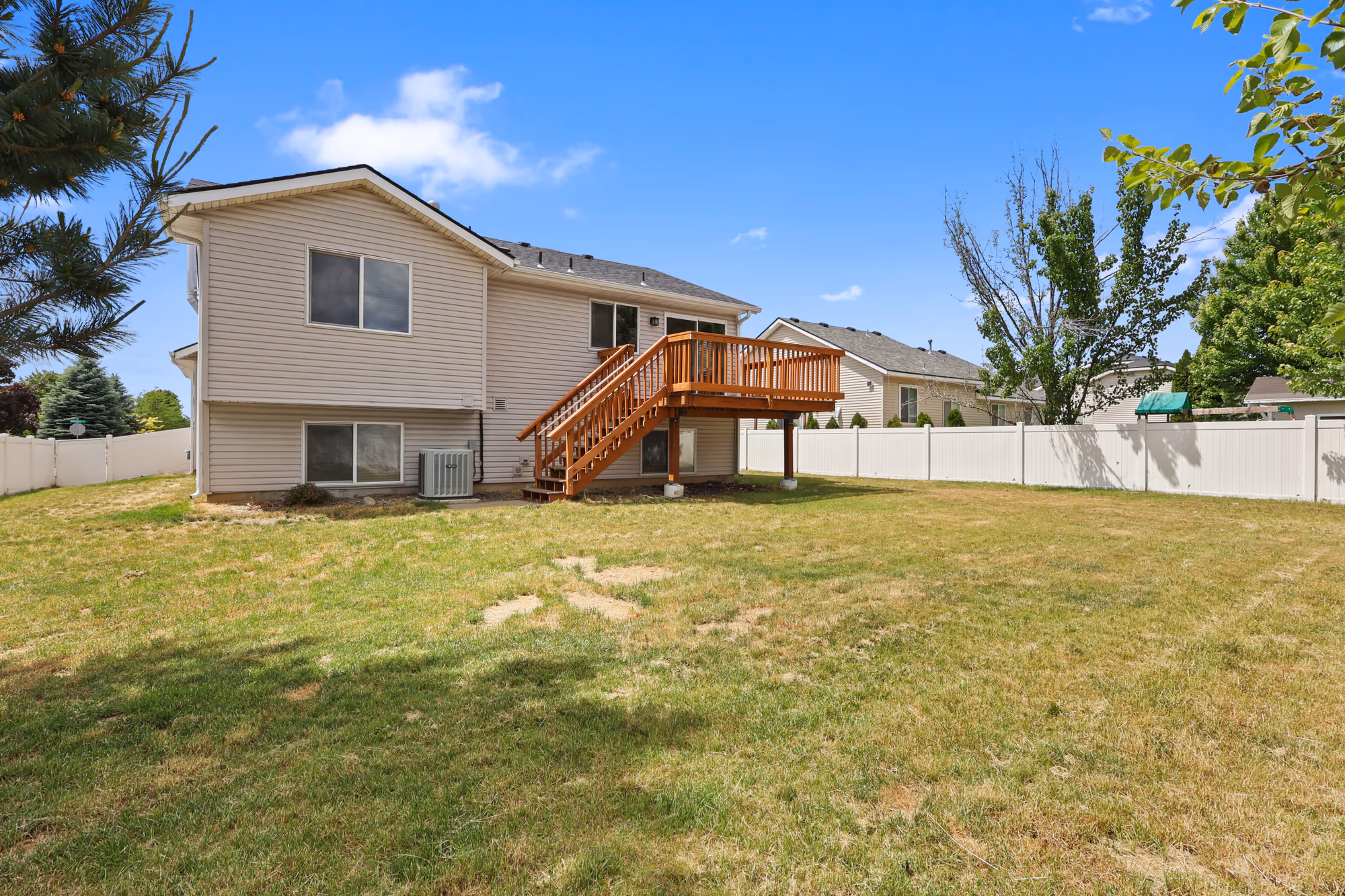 Rear exterior of a home with a deck and open lawn