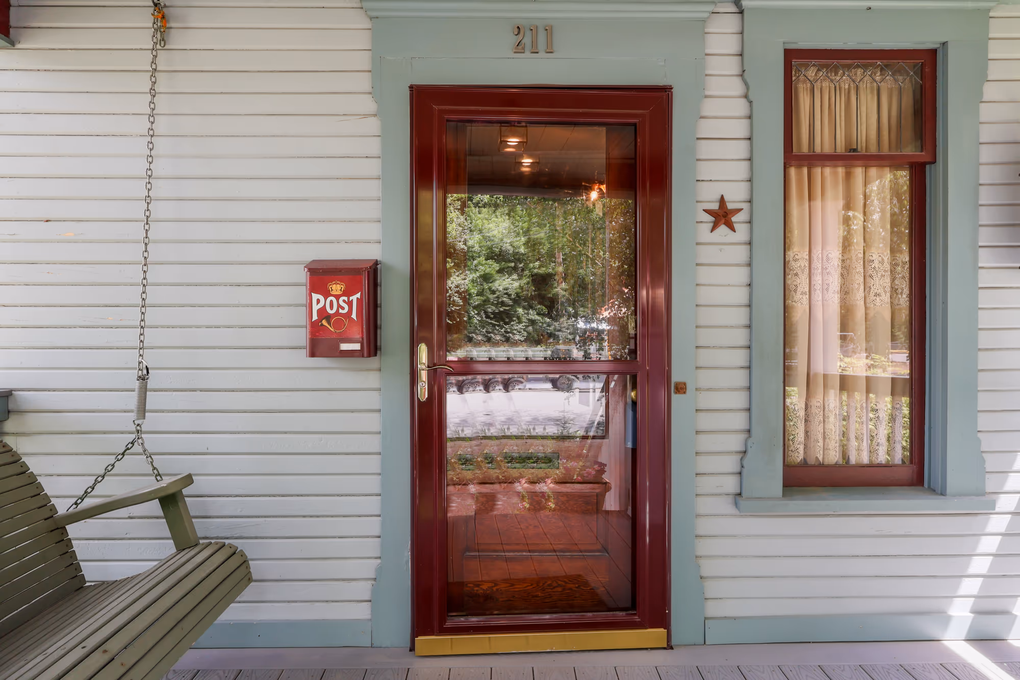 Covered porch with a swing beside a classic red front door