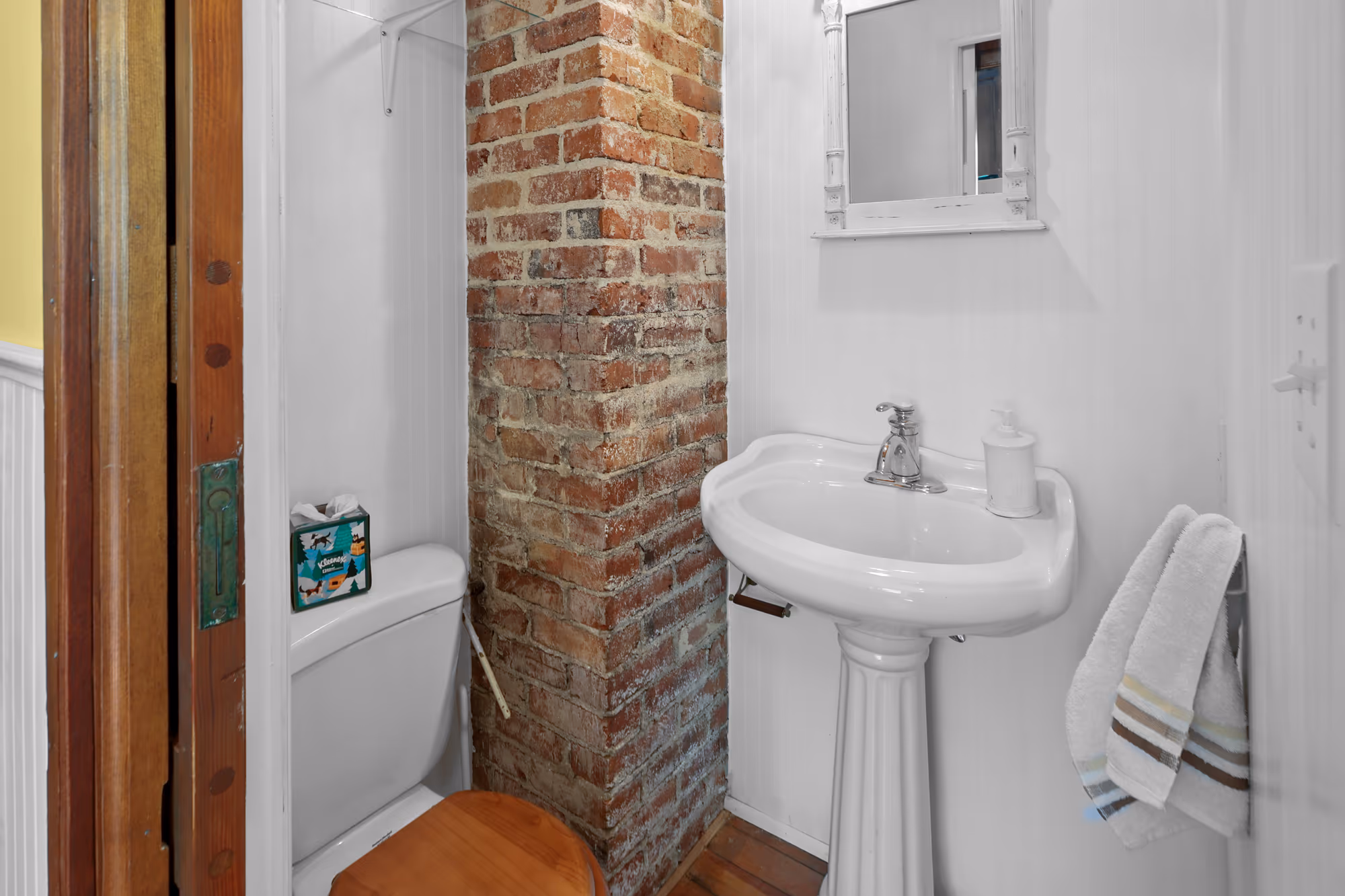 Bathroom detail with an exposed brick chimney and pedestal sink