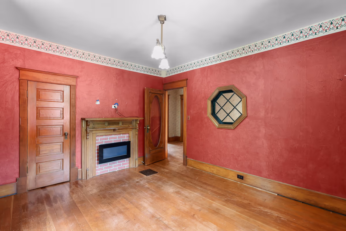 Sitting room with crimson walls, a fireplace, and an octagon window
