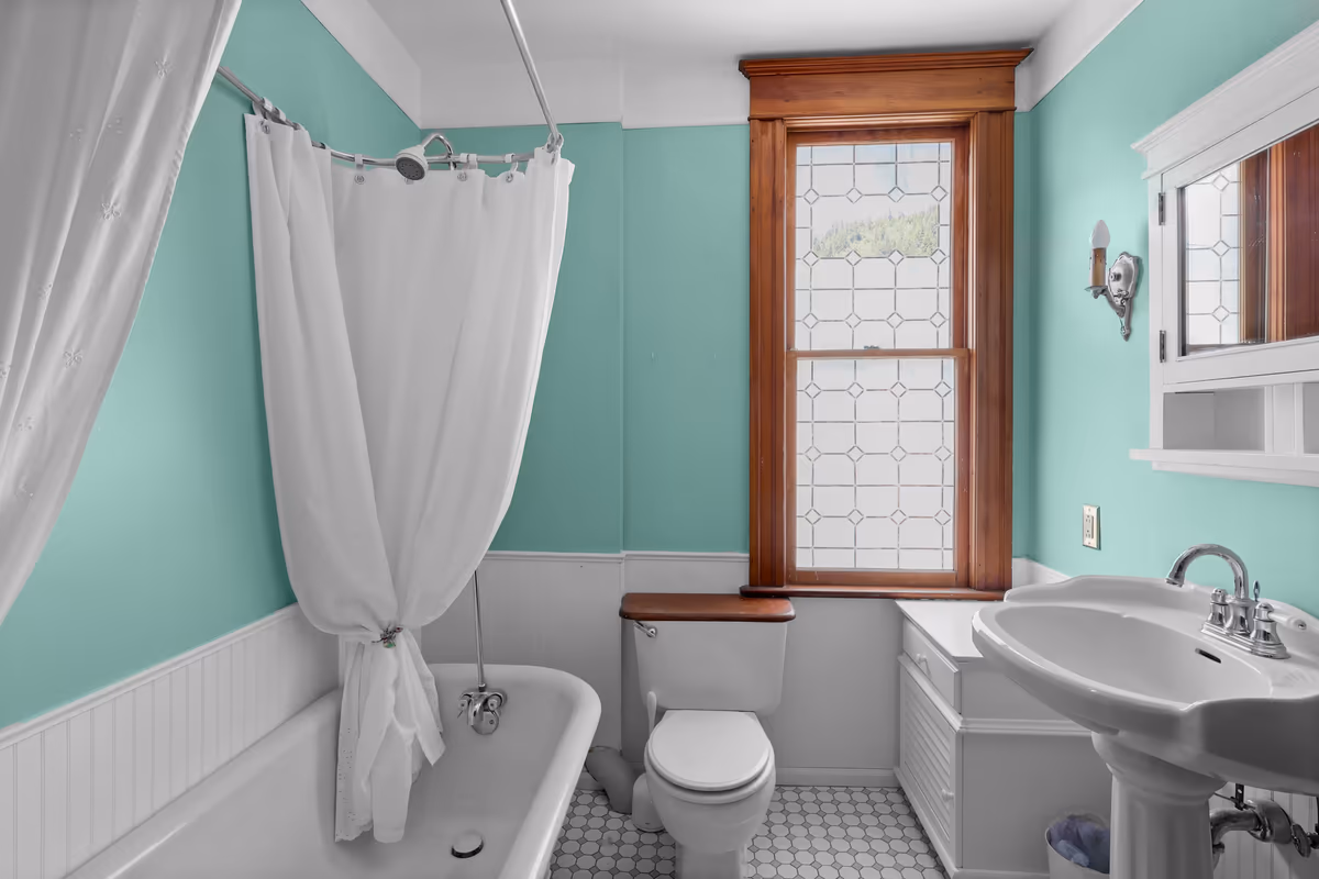 Turquoise bathroom with a clawfoot tub and leaded-glass window