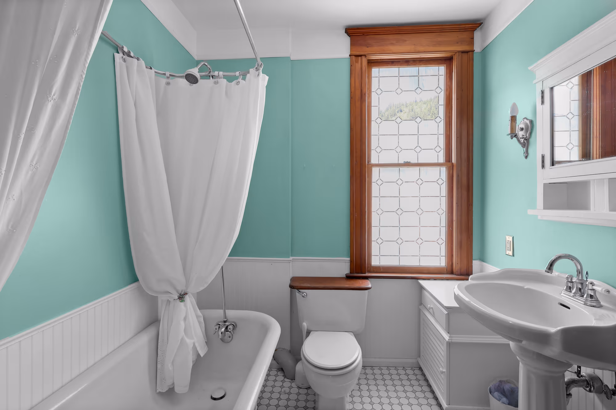 Turquoise bathroom with a clawfoot tub and leaded-glass window