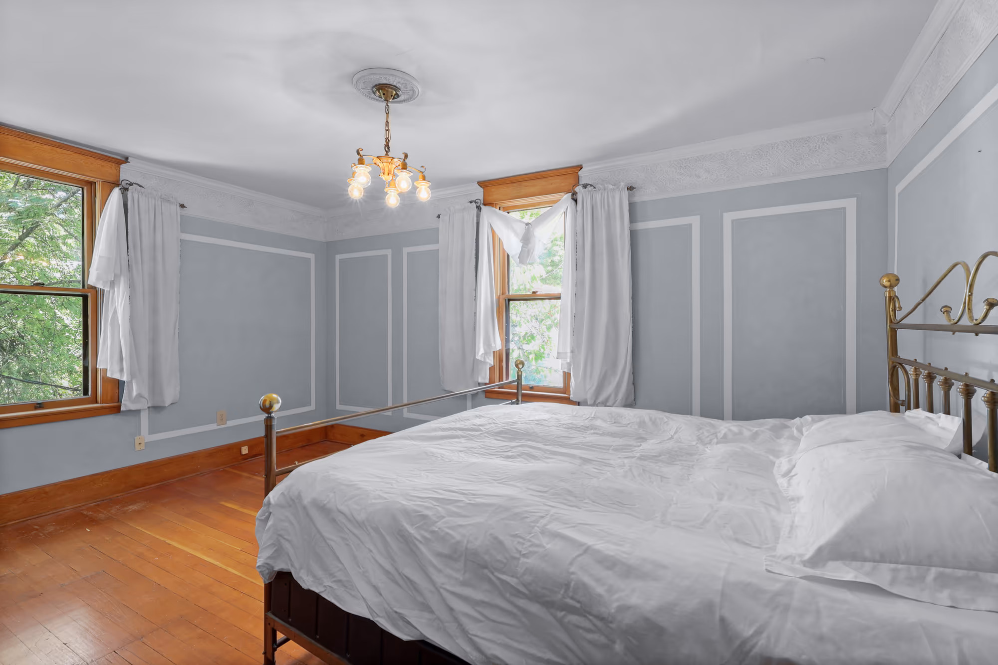Bedroom with a brass bed and tree-lined window light