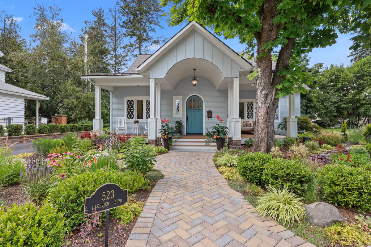 Light-blue cottage with an arched entry and a landscaped stone walkway