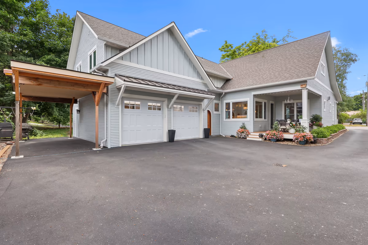 Rear exterior and garage overlooking a broad paved driveway