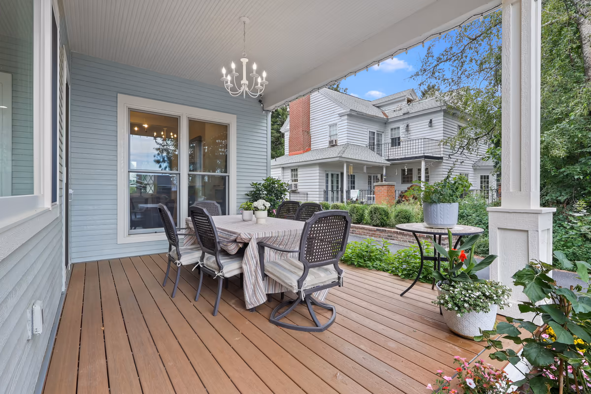 Covered porch dining area with a neighboring home beyond