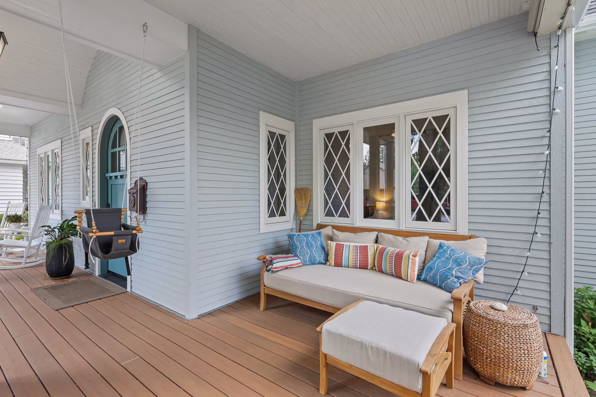 Covered porch with cushioned seating, blue siding, and wood decking