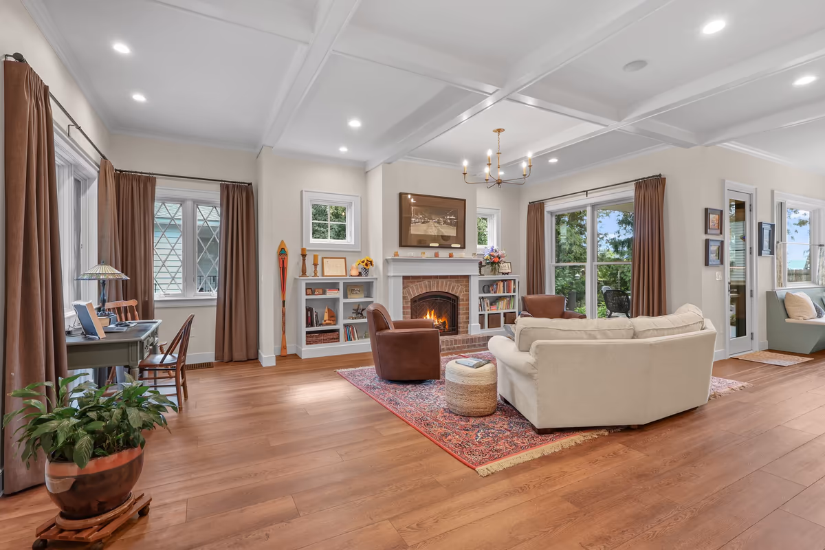 Bright living room with a lit brick fireplace and white ceiling beams
