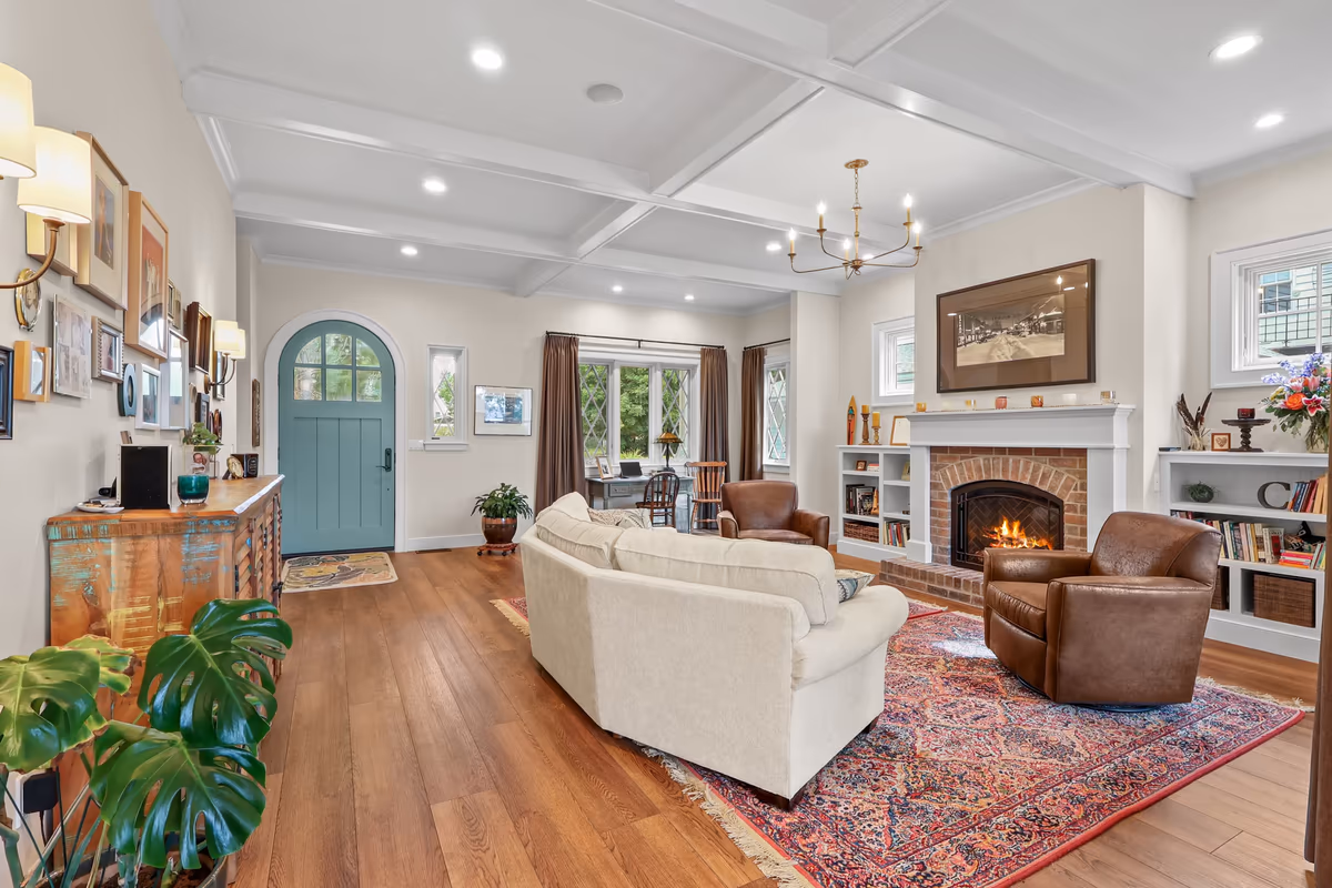 Furnished living room with a blue entry door, fireplace, and white ceiling beams