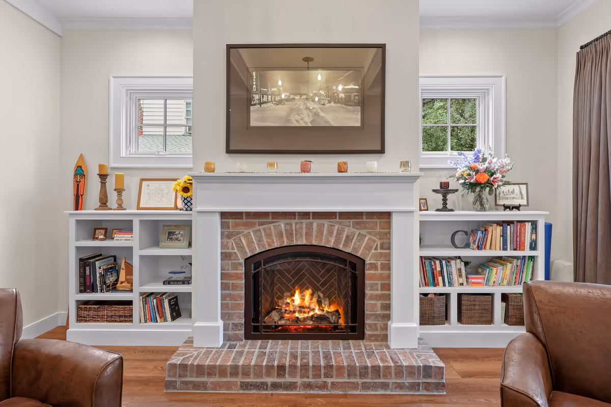Lit brick fireplace framed by white built-in bookshelves