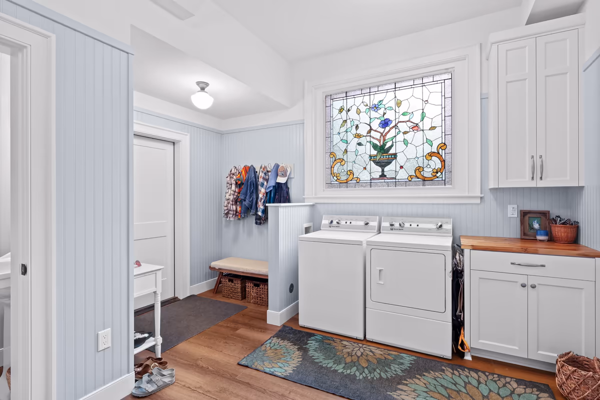 Laundry room with white cabinetry and a floral stained-glass window