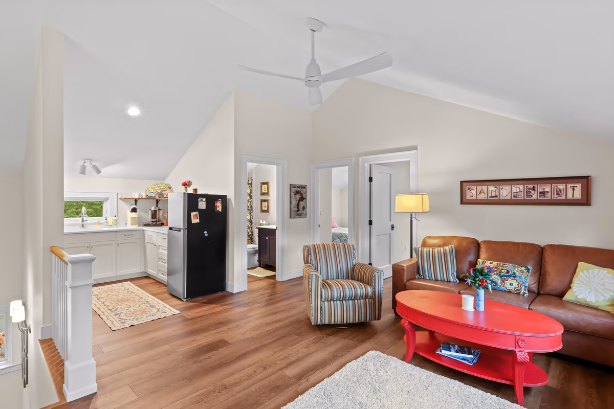 Connected upstairs living area and kitchen with a refrigerator beside the doorway