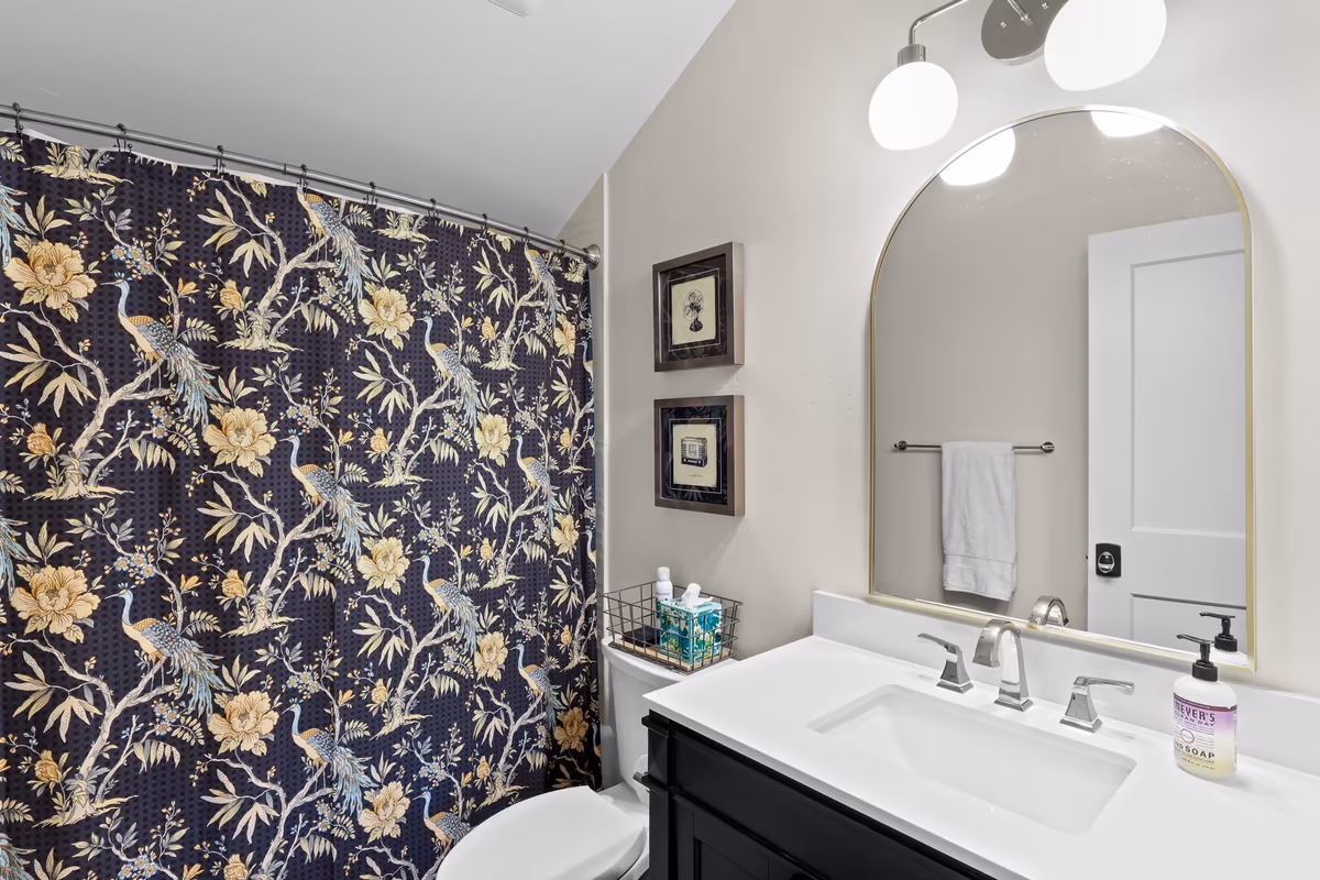Bathroom with a floral shower curtain and rounded vanity mirror