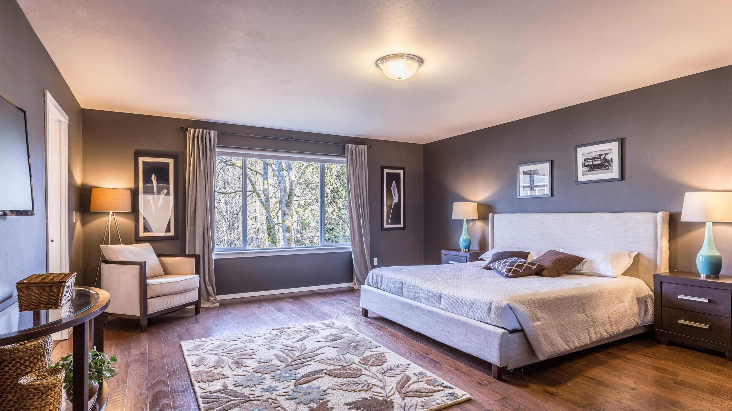 Staged bedroom with neutral furnishings, accent seating, and artwork