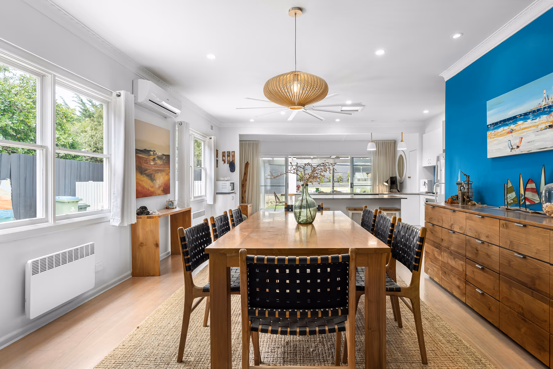 Bright dining room with pendant light, leather chairs, and a blue accent wall
